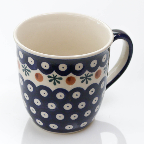 Navy ceramic mug with white polka dot pattern and black handle, front view