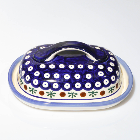 Navy blue ceramic dish with white polka dot pattern and gold rim, oval shape with handles on sides