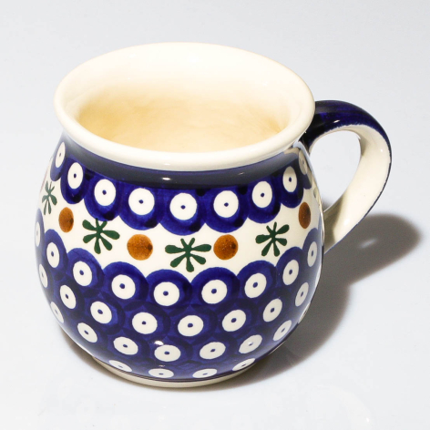Dark blue ceramic mug with white polka dots and yellow floral accent, cream interior, front view