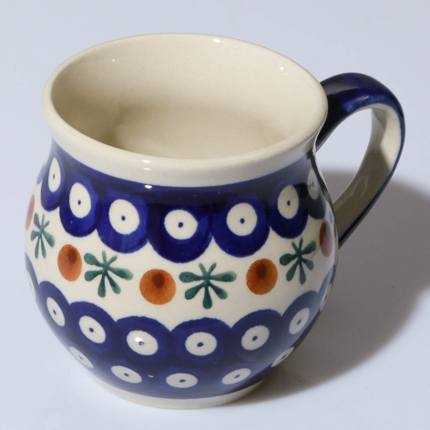 Ceramic jug with deep blue glaze decorated with white dots and colorful floral motifs, cream interior and handle