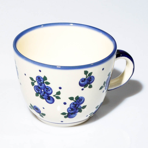 Cream ceramic teacup with blue floral motifs and rim, featuring a dark blue handle, angled front view