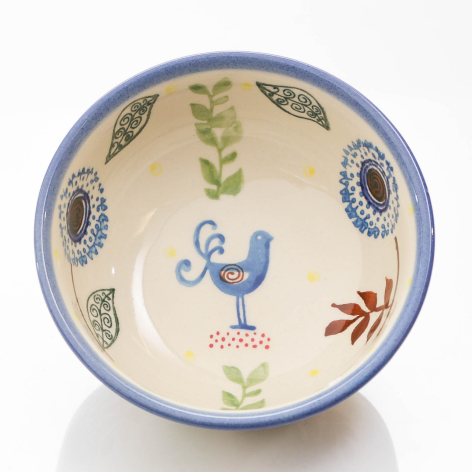Blue-rimmed ceramic bowl with cream interior featuring hand-painted blue bird, botanical motifs, and decorative patterns