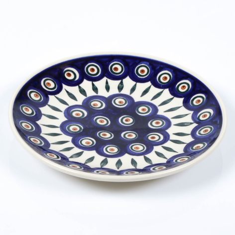 Navy blue ceramic plate with white floral medallion pattern and scalloped rim, angled three-quarter view