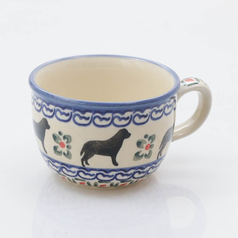 Cream ceramic cup with blue decorative border and silhouettes of dogs and floral motifs, front view