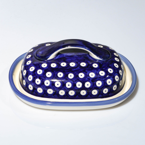 Navy blue ceramic colander with white polka dot pattern and dual handles, top view showing perforated bowl design