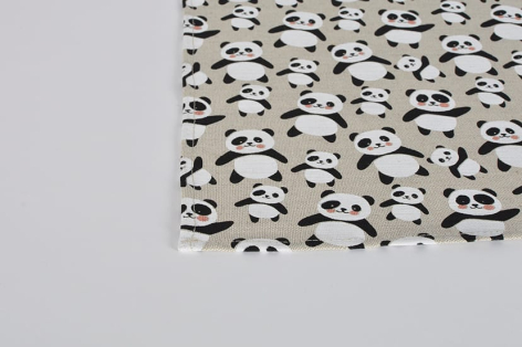 Cream textile with black geometric pattern, corner detail showing folded edge against neutral background