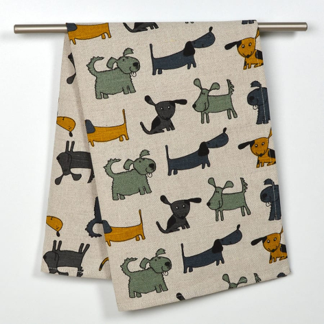 Cream linen textile with scattered multicolored dog silhouettes in green, black, and gold tones, folded display