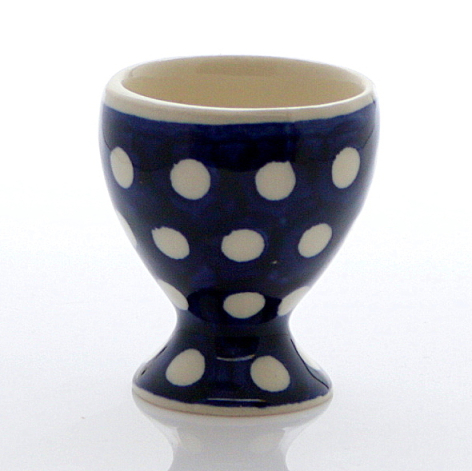 Navy blue ceramic egg cup with cream polka dots and pedestal base, front view