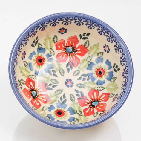 Ceramic bowl with cream-colored interior decorated with red and blue floral motifs, blue border rim, top view