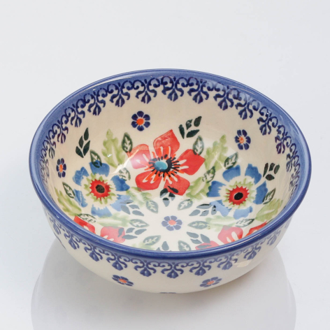 Blue and cream ceramic bowl with hand-painted floral motifs and decorative patterned rim, angled three-quarter view