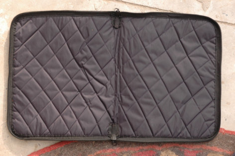 Pochette matelassée grise en cuir ouvert à plat, vue de dessus montrant le motif de piqûre losangée