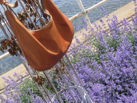 Brown leather bag hanging above purple lavender fields in sunlight