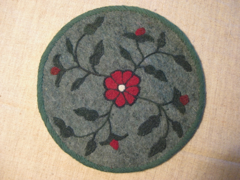 Dessous de verre rond en feutre gris avec broderies florales rouges et détail central en perles rouges