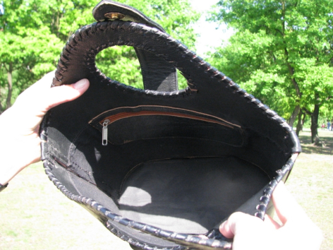 Black leather bucket bag with patterned textile lining, open view showing spacious interior compartment