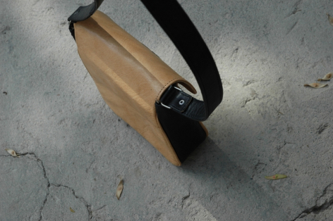 Wooden rectangular block with black fabric strap, angled view on gray surface