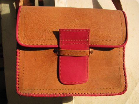 Tan leather shoulder bag with contrasting red front flap closure and decorative stitching detail, front view