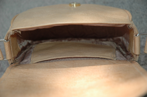 Beige leather shoulder bag open to show light tan interior lining and structured top closure