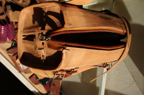Tan leather backpack viewed from above, showing open main compartment and interior organization pockets