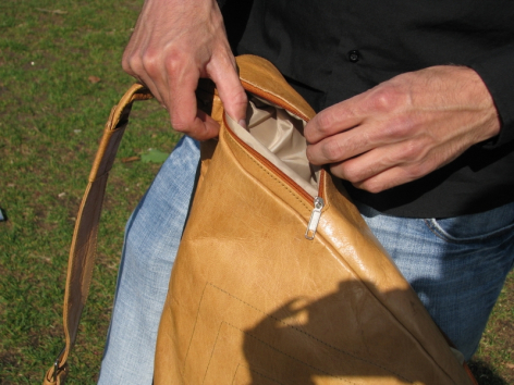 Sac en cuir beige montrant les détails des coutures et des poignées, tenu ouvert par deux mains
