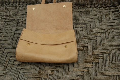 Sac en cuir beige clair avec rabat arrondi, vue de face sur surface texturée