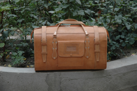 Valise en cuir marron clair vue de face, avec poignée supérieure et fermoirs métalliques