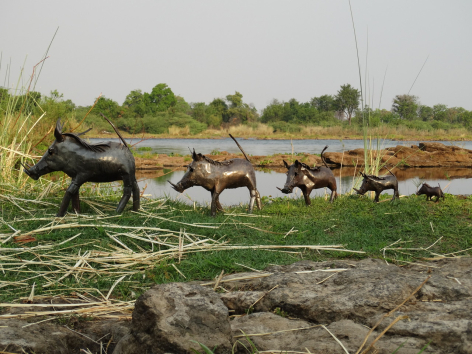 Herd of brown horses grazing in green pasture beside water under overcast sky