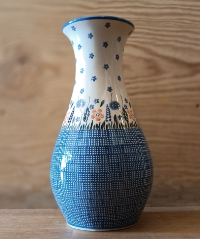 Blue and white ceramic vase with textured woven pattern and dotted rim detail, displayed against wooden background