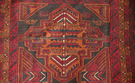 Red and gold hand-woven textile with geometric diamond pattern and traditional Central Asian design