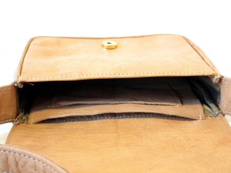Tan leather bag open from above showing black interior compartment and structured flap closure