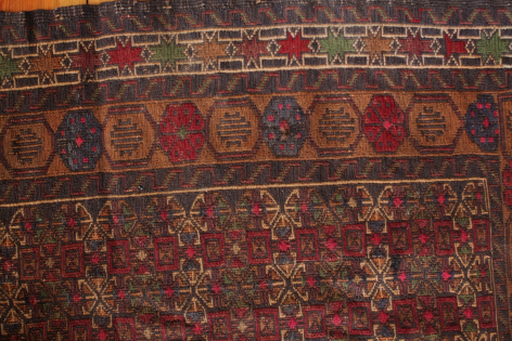Deep red wool textile with traditional geometric patterns and decorative border detail, flat lay view
