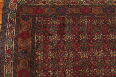 Deep red woven textile with intricate geometric pattern and ornate border detail, flat lay view
