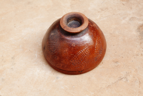 Terracotta ceramic bowl with rounded form and glossy reddish-brown glaze, viewed from above