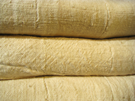 Stacked natural linen textiles with woven texture and visible thread patterns in neutral cream tones