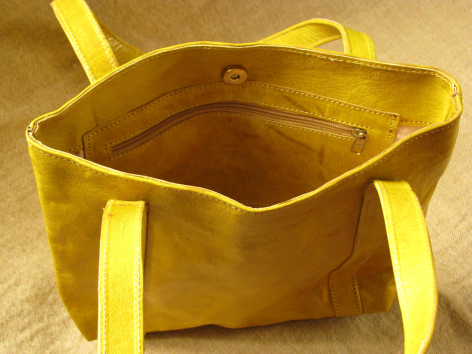 Golden yellow leather tote bag with dual handles, viewed from above showing interior and suede texture