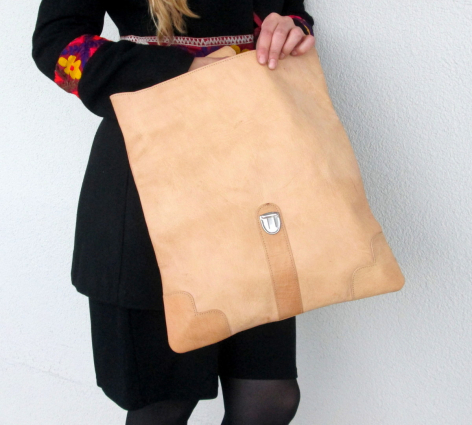 Hellbraune Ledertasche mit rechteckiger Form und minimalistischem Design, von vorne in Trageposition gezeigt