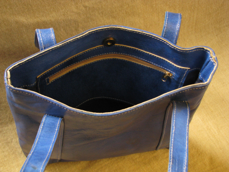 Navy leather tote bag with blue fabric handles, open top view showing dark interior
