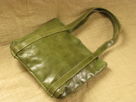 Green leather tote bag with dual handles, displayed flat from above on neutral background