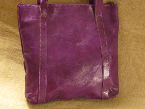 Purple leather tote bag with handles, front view showing worn patina finish and vertical stitch detailing