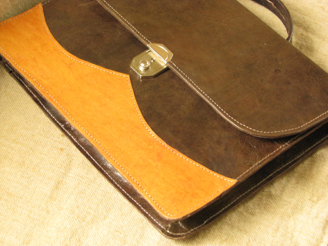 Brown leather bag with golden-yellow interior, open to reveal lining and metal clasp detail, top view