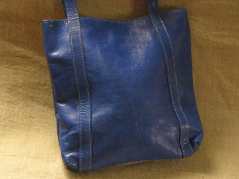 Deep blue leather tote bag with dual handles, front view showing smooth worn patina and vertical seam detailing