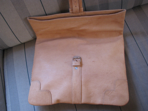 Tan leather shoulder bag with front flap and silver metal clasp, shown open from above