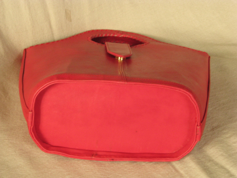 Rote Ledertasche mit abgerundeter Form und großem Frontfach, Draufsicht auf hellem Untergrund