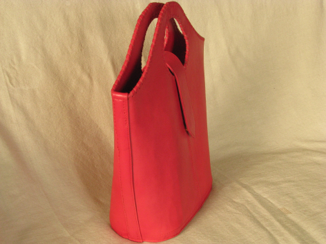 Red felt tote bag with handles, viewed from the side against a cream background