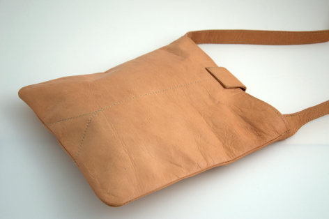 Hellbraune Ledertasche mit Schultergurt, schräge Vorderansicht auf weißem Hintergrund