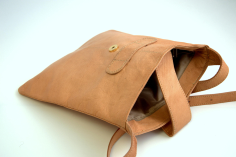 Tan leather shoulder bag with flap closure and adjustable straps, viewed from front angle