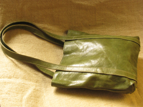 Olive green leather crossbody bag with front transparent pocket, viewed from above on neutral background