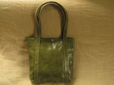 Olive green leather tote bag with dark handles, front view showing textured patina finish