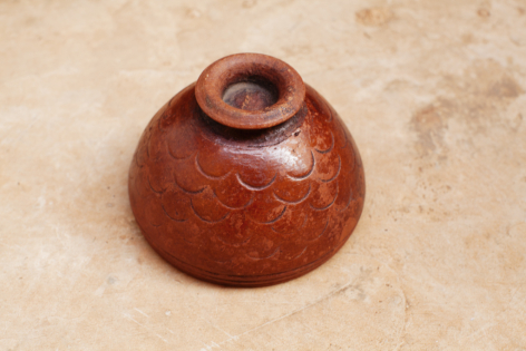 Terracotta ceramic bowl with rounded shape and wide rim, viewed from above on neutral background