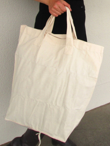 Cream linen tote bag with black handles held open, front view