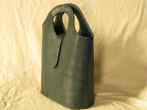 Olive green leather tote bag with dual handles, standing upright against cream backdrop